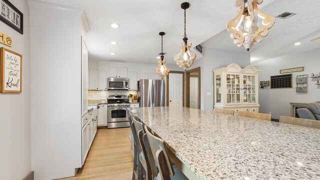 241 Mullet Dr, Freeport, FL 32439 - kitchen with appliances with stainless steel finishes, recessed lighting, light wood finished floors, backsplash, and a breakfast bar