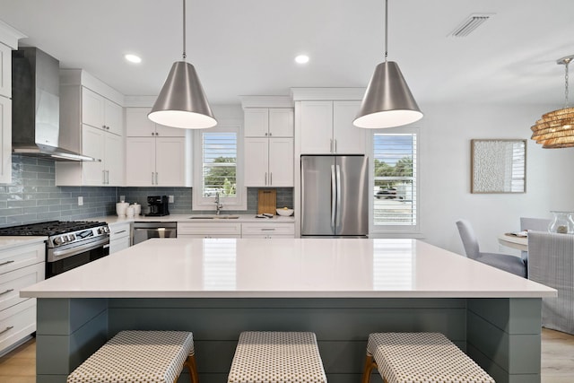 278 Dockside Dr, Port St Joe, FL 32456 - kitchen with stainless steel appliances, wall chimney range hood, a kitchen breakfast bar, tasteful backsplash, and recessed lighting