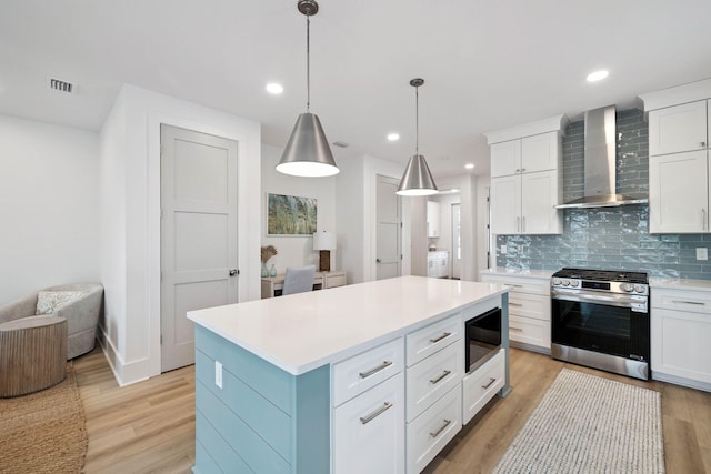 278 Dockside Dr, Port St Joe, FL 32456 - kitchen with gas stove, wall chimney range hood, black microwave, light wood finished floors, and light countertops