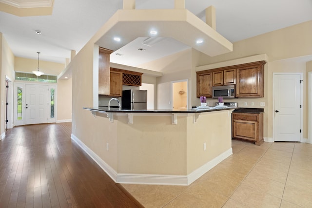 201 Pinque Coat Ct, Crestview, FL 32536 - kitchen featuring stainless steel appliances, dark countertops, a breakfast bar area, brown cabinets, and a peninsula