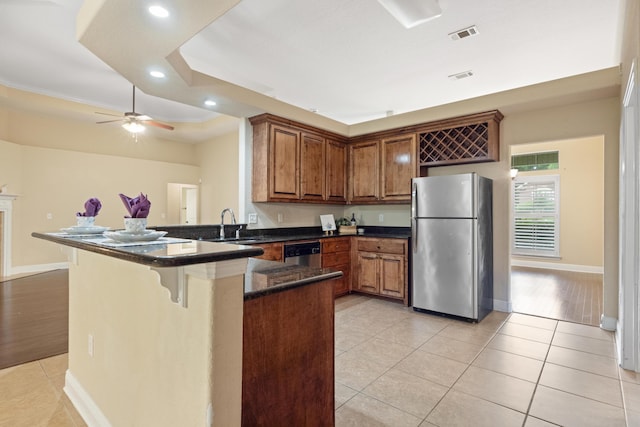 201 Pinque Coat Ct, Crestview, FL 32536 - kitchen featuring appliances with stainless steel finishes, a peninsula, light tile patterned floors, a kitchen bar, and brown cabinetry