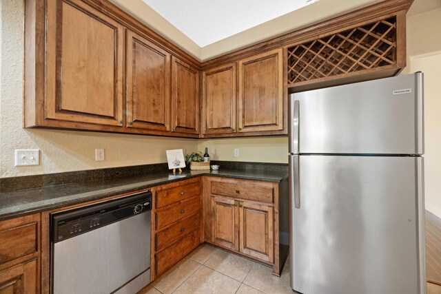 201 Pinque Coat Ct, Crestview, FL 32536 - kitchen featuring stainless steel appliances, brown cabinets, dark countertops, and light tile patterned floors