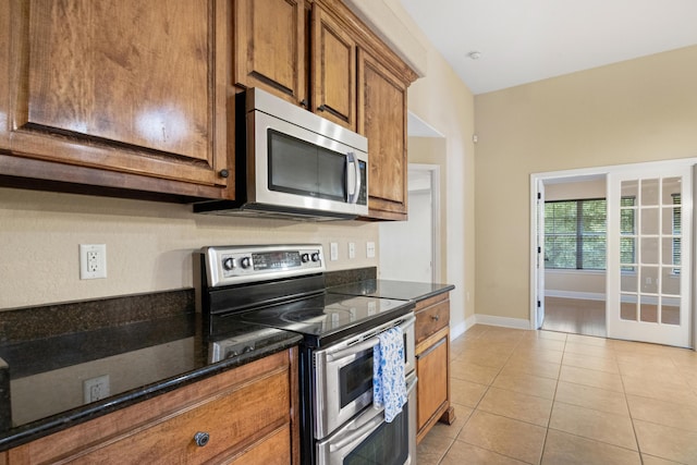 201 Pinque Coat Ct, Crestview, FL 32536 - kitchen featuring appliances with stainless steel finishes, brown cabinetry, light tile patterned floors, and dark stone counters
