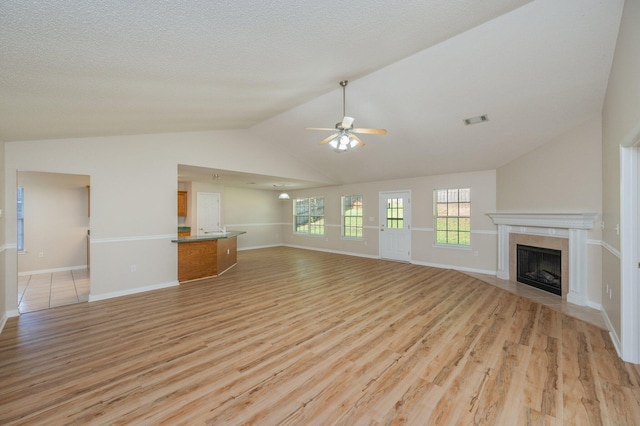 407 Tobago Ct, Crestview, FL 32536 - unfurnished living room with light wood-style floors, a tiled fireplace, a ceiling fan, vaulted ceiling, and baseboards