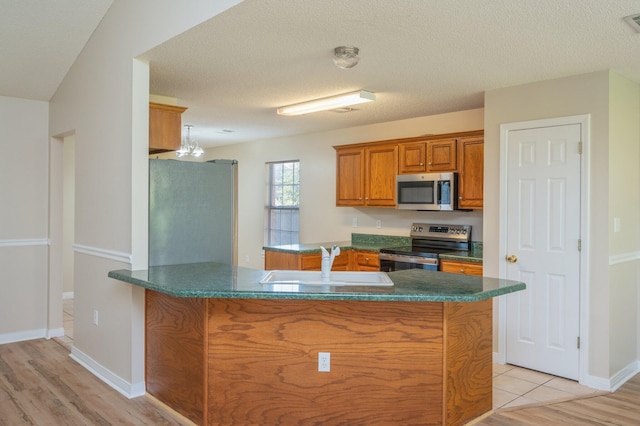 407 Tobago Ct, Crestview, FL 32536 - kitchen with appliances with stainless steel finishes, a sink, brown cabinets, and light wood finished floors