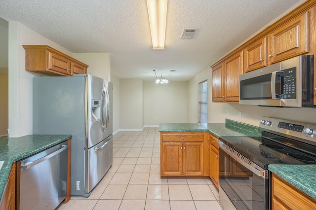 407 Tobago Ct, Crestview, FL 32536 - kitchen with appliances with stainless steel finishes, a peninsula, a textured ceiling, light tile patterned flooring, and dark countertops