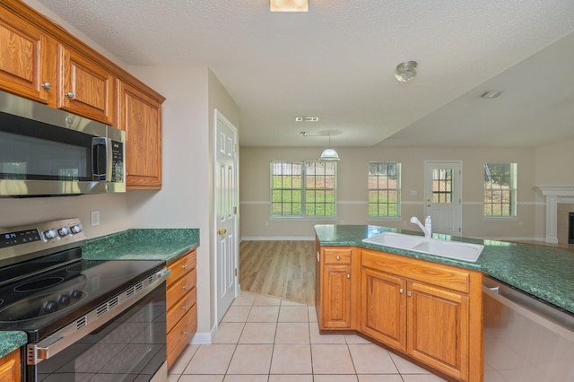 407 Tobago Ct, Crestview, FL 32536 - kitchen featuring appliances with stainless steel finishes, a sink, brown cabinets, light tile patterned floors, and dark countertops