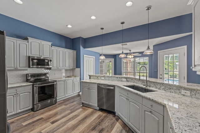 2741 Creeks Edge Ln, Navarre, FL 32566 - kitchen featuring stainless steel appliances, a sink, decorative backsplash, wood finished floors, and hanging light fixtures