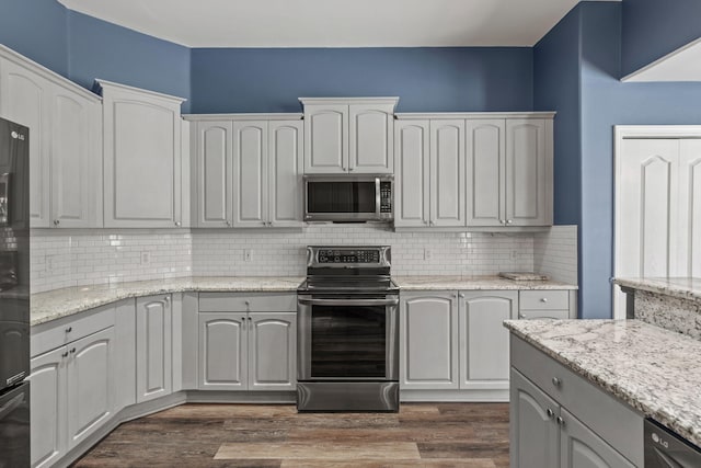 2741 Creeks Edge Ln, Navarre, FL 32566 - kitchen featuring appliances with stainless steel finishes, tasteful backsplash, dark wood finished floors, and light stone counters