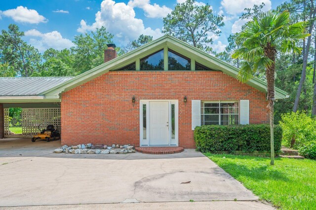2226 W James Lee Blvd, Crestview, FL 32536 - view of front of house featuring a chimney, brick siding, driveway, an attached carport, and a metal roof