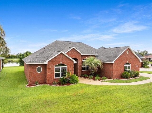 203 Landings Dr, Lynn Haven, FL 32444 - ranch-style house with brick siding, roof with shingles, a front lawn, and a water view