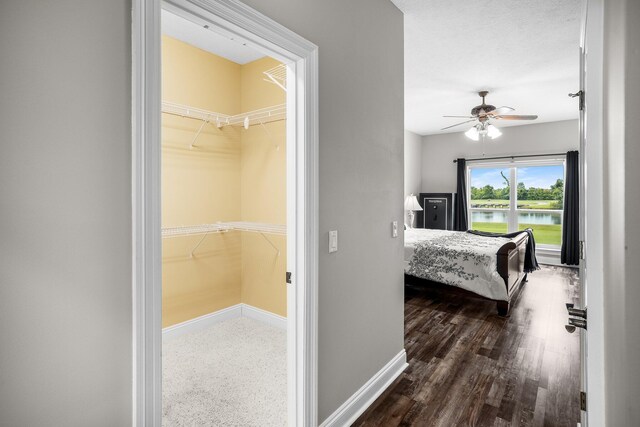 203 Landings Dr, Lynn Haven, FL 32444 - bedroom with a water view, baseboards, dark wood finished floors, a spacious closet, and ceiling fan