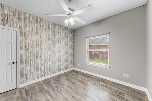 203 Landings Dr, Lynn Haven, FL 32444 - unfurnished room featuring an accent wall, wallpapered walls, baseboards, wood finished floors, and a ceiling fan
