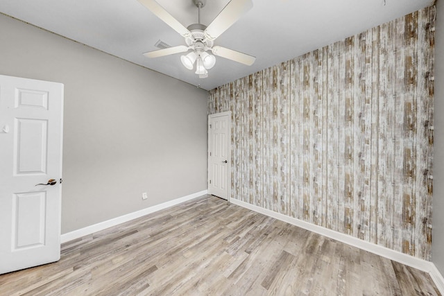 203 Landings Dr, Lynn Haven, FL 32444 - spare room with wallpapered walls, baseboards, wood finished floors, an accent wall, and a ceiling fan
