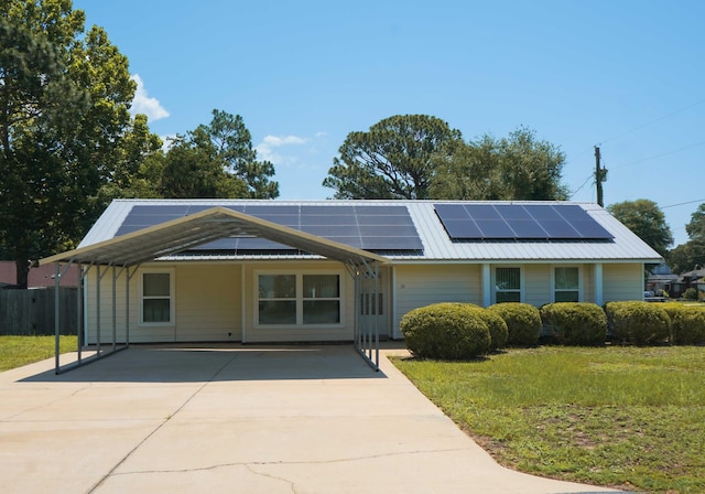 74 8th St, Shalimar, FL 32579 - single story home featuring concrete driveway, solar panels, a metal roof, and a carport