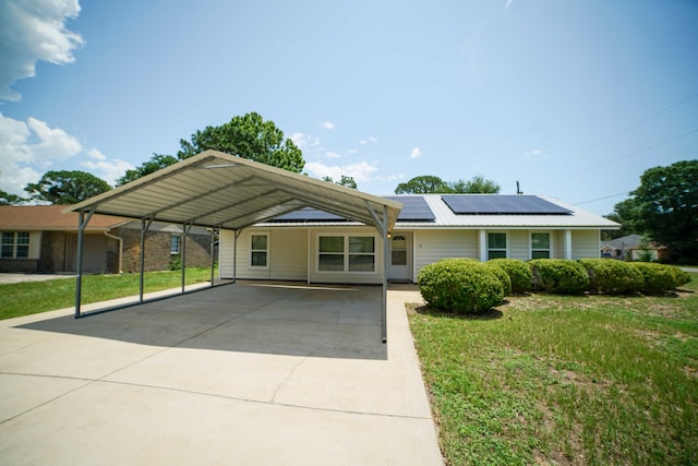 74 8th St, Shalimar, FL 32579 - single story home featuring concrete driveway, a front lawn, roof mounted solar panels, and a carport