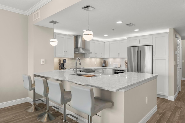 17281 Front Beach Rd Unit 1206, Panama City Beach, FL 32413 - kitchen with wall chimney exhaust hood, high quality fridge, a peninsula, wood finish floors, and recessed lighting
