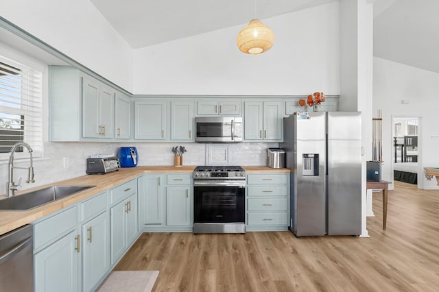 413 Colorado Dr, Mexico Beach, FL 32456 - kitchen featuring stainless steel appliances, a sink, high vaulted ceiling, tasteful backsplash, and light wood-style floors