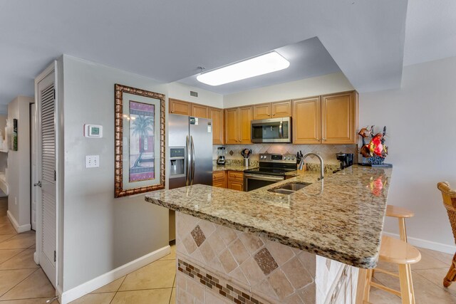 866 Santa Rosa Blvd Unit 302, Fort Walton Beach, FL 32548 - kitchen with stainless steel appliances, a peninsula, light stone counters, and light tile patterned floors