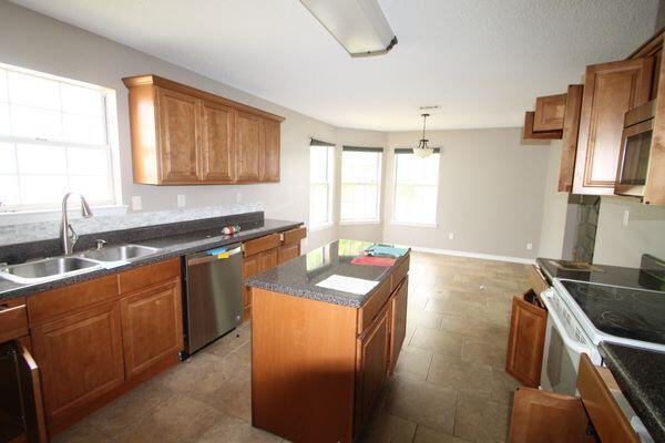 116 Nicole Ln, Crestview, FL 32539 - kitchen featuring stainless steel appliances, healthy amount of natural light, brown cabinetry, and a center island