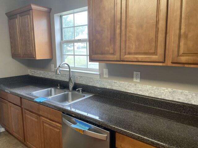 116 Nicole Ln, Crestview, FL 32539 - kitchen featuring stainless steel dishwasher, dark countertops, plenty of natural light, and brown cabinetry