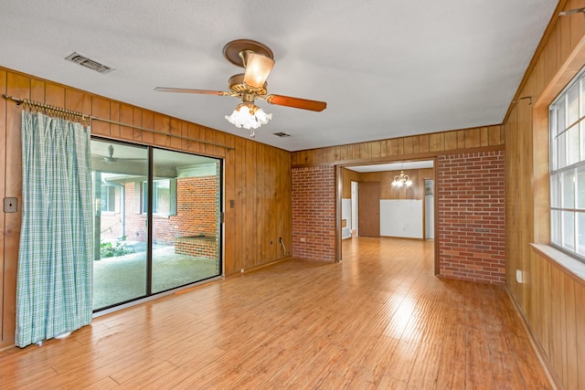 19 Bayview Dr, Shalimar, FL 32579 - empty room with wooden walls, plenty of natural light, light wood-style floors, a ceiling fan, and a chandelier