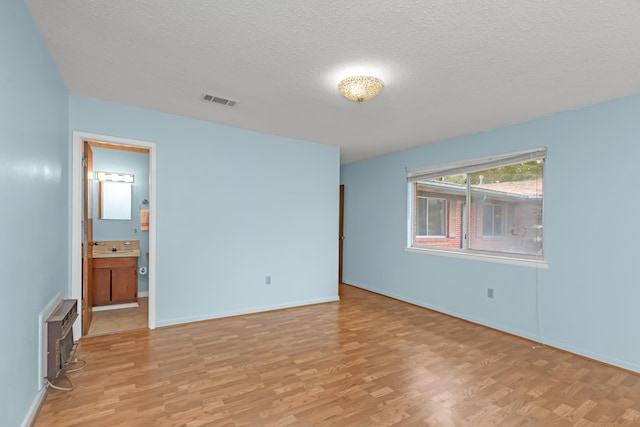 19 Bayview Dr, Shalimar, FL 32579 - unfurnished bedroom with a textured ceiling, light wood finished floors, and connected bathroom