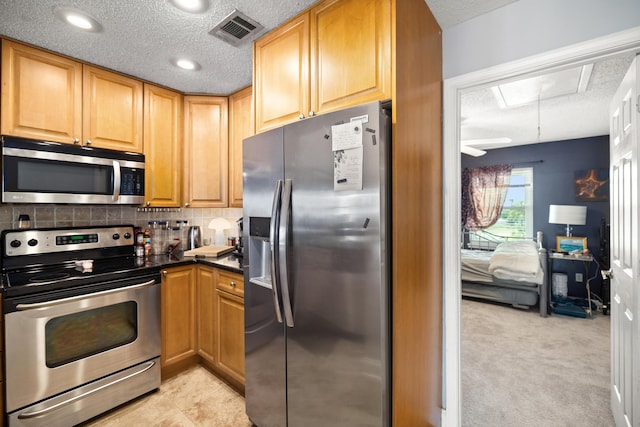 113 Durango Rd, Destin, FL 32541 - kitchen featuring stainless steel appliances, a textured ceiling, decorative backsplash, light colored carpet, and dark countertops