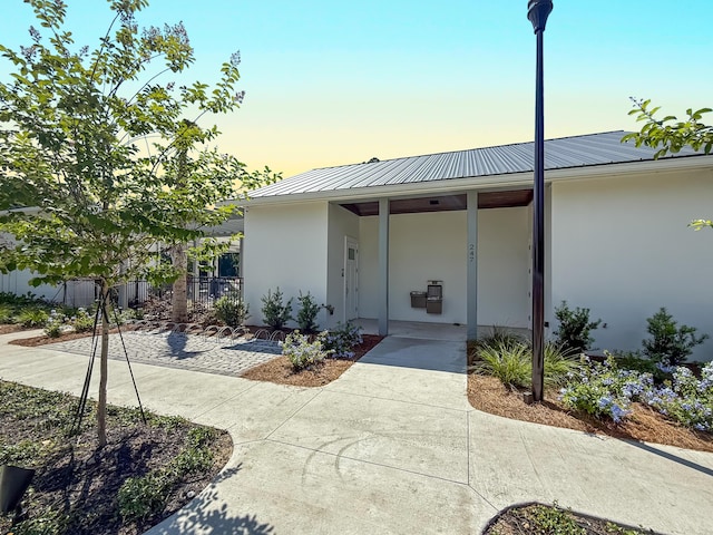 458 Linkside Pl, Miramar Beach, FL 32550 - exterior entry at dusk featuring stucco siding and metal roof