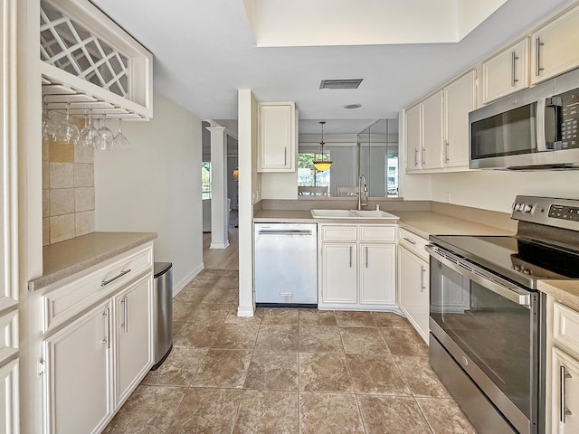 458 Linkside Pl, Miramar Beach, FL 32550 - kitchen featuring stainless steel appliances, a sink, light countertops, decorative columns, and pendant lighting
