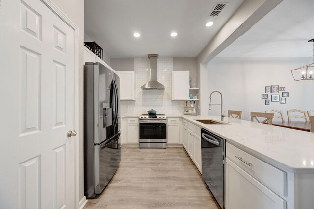 233 Sand Oak Blvd, Panama City Beach, FL 32413 - kitchen with stainless steel appliances, wall chimney exhaust hood, a sink, a peninsula, and white cabinetry