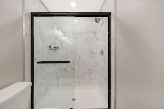 233 Sand Oak Blvd, Panama City Beach, FL 32413 - bathroom featuring toilet, a shower stall, and a textured wall