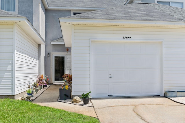 6922 Sea Turtle Cir, Navarre, FL 32566 - entrance to property with a shingled roof, driveway, a garage, and stucco siding
