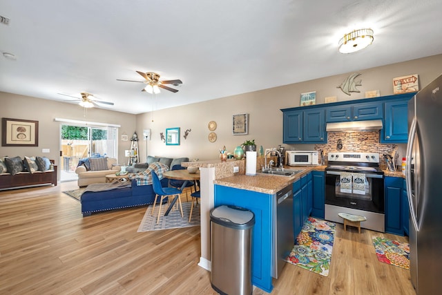 6922 Sea Turtle Cir, Navarre, FL 32566 - kitchen featuring stainless steel appliances, open floor plan, blue cabinets, under cabinet range hood, and a peninsula