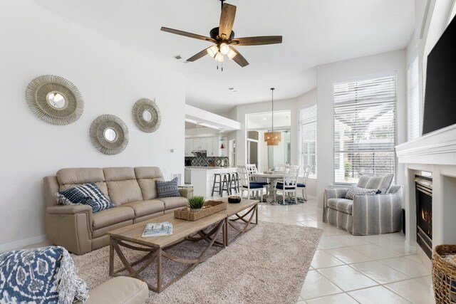 527 Indigo Loop, Miramar Beach, FL 32550 - living area with light tile patterned flooring, a ceiling fan, a warm lit fireplace, and baseboards