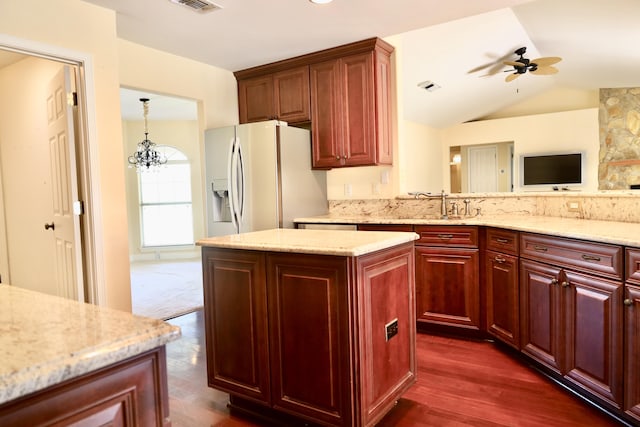 222 Wekiva Cv, Destin, FL 32541 - kitchen with white refrigerator with ice dispenser, reddish brown cabinets, light stone countertops, vaulted ceiling, and a kitchen island