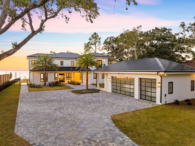 253 Driftwood Point Rd, Santa Rosa Beach, FL 32459 - view of front of house featuring stucco siding, an attached garage, metal roof, decorative driveway, and a water view
