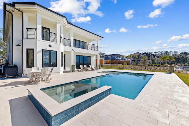 253 Driftwood Point Rd, Santa Rosa Beach, FL 32459 - rear view of house with a balcony, a patio area, a pool with connected hot tub, and stucco siding