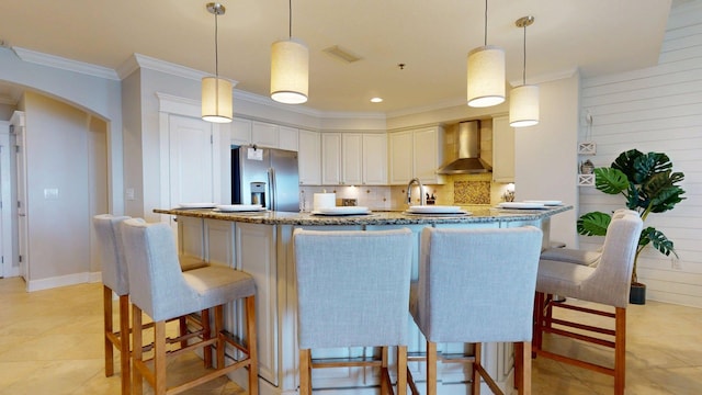 11807 Front Beach Rd Unit 1- 2204, Panama City Beach, FL 32407 - kitchen with stainless steel refrigerator with ice dispenser, wall chimney exhaust hood, ornamental molding, arched walkways, and light stone countertops