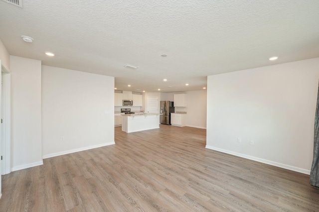 4652 Honor Guard Way, Crestview, FL 32539 - unfurnished living room with light wood-style floors, recessed lighting, and a textured ceiling