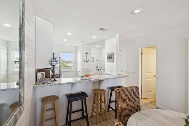 23011 Front Beach Rd Unit E-20, Panama City Beach, FL 32413 - kitchen with white cabinets, light stone counters, a kitchen bar, recessed lighting, and a peninsula