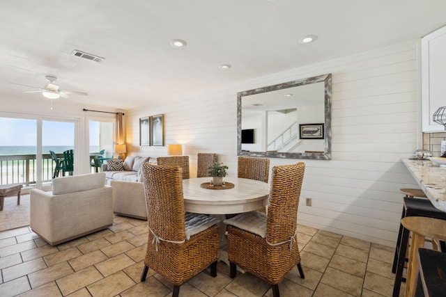 23011 Front Beach Rd Unit E-20, Panama City Beach, FL 32413 - dining area with a ceiling fan, wood walls, and a water view