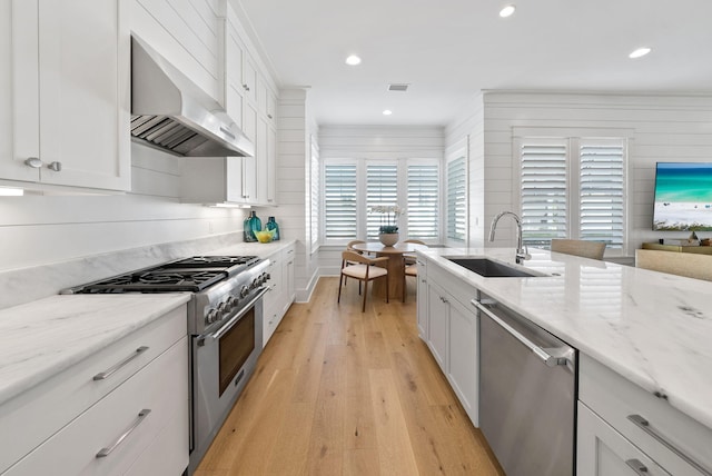 339 Pathways Dr, Inlet Beach, FL 32461 - kitchen featuring stainless steel appliances, a sink, wall chimney exhaust hood, light wood-style flooring, and white cabinetry