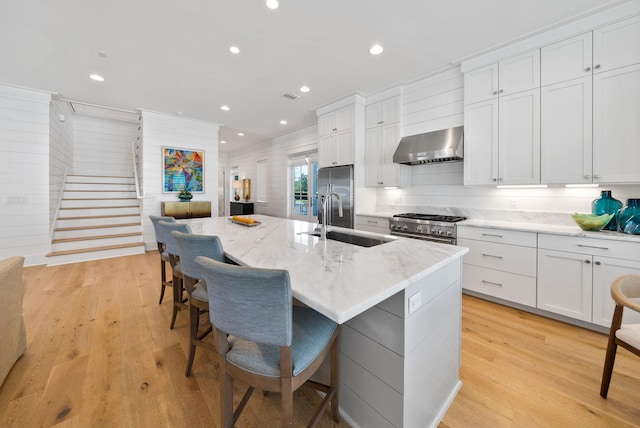 339 Pathways Dr, Inlet Beach, FL 32461 - kitchen featuring wall chimney range hood, a sink, appliances with stainless steel finishes, an island with sink, and a breakfast bar