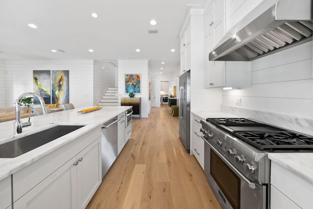 339 Pathways Dr, Inlet Beach, FL 32461 - kitchen with appliances with stainless steel finishes, a sink, range hood, light wood-style flooring, and white cabinets