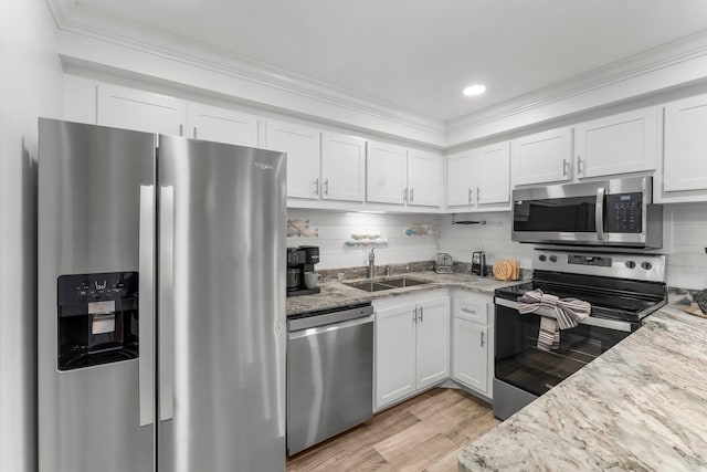 23223 Front Beach Rd # 335, Panama City Beach, FL 32413 - kitchen featuring appliances with stainless steel finishes, a sink, white cabinets, light wood-style flooring, and ornamental molding