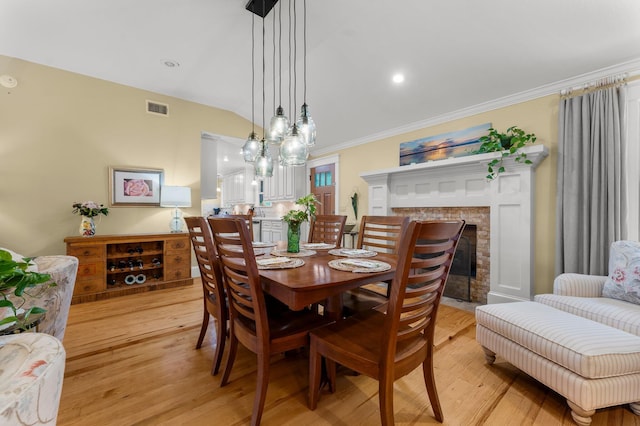 619 Pitts Bayshore Dr, Freeport, FL 32439 - dining room featuring light wood-type flooring, a brick fireplace, crown molding, and lofted ceiling