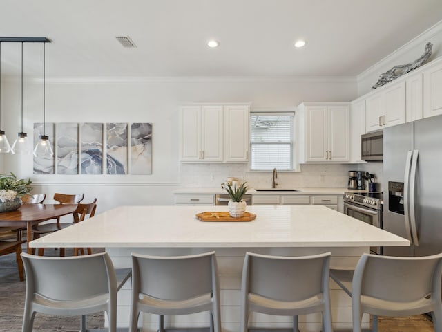 221 Seacrest Beach Blvd E, Seacrest, FL 32461 - kitchen featuring stainless steel appliances, a breakfast bar area, ornamental molding, white cabinetry, and tasteful backsplash