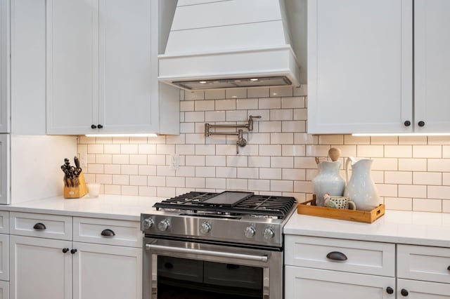 1502 Coriander Ln, Niceville, FL 32578 - kitchen with stainless steel stove, custom exhaust hood, white cabinets, and decorative backsplash