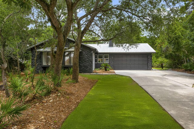 81 Canal St, Santa Rosa Beach, FL 32459 - mid-century modern home with stone siding, concrete driveway, an attached garage, a metal roof, and a chimney